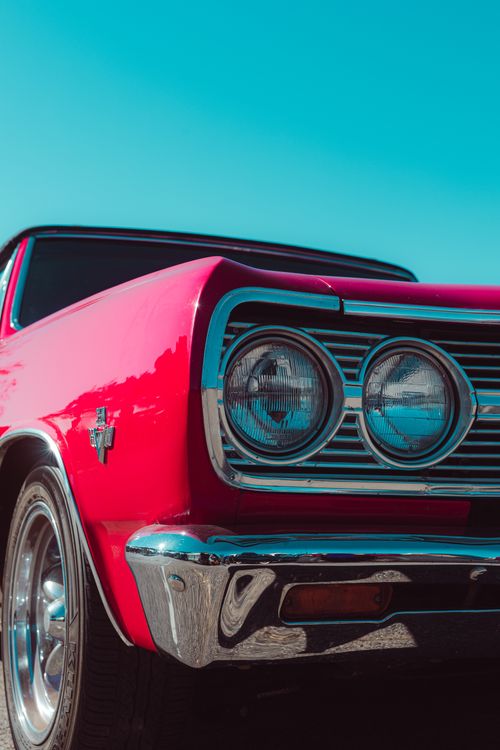 Free Detailed view of a red vintage classic car's front under clear blue sky. Stock Photo