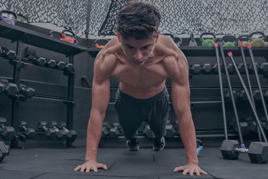 A muscular young man doing push ups in a modern gym setting