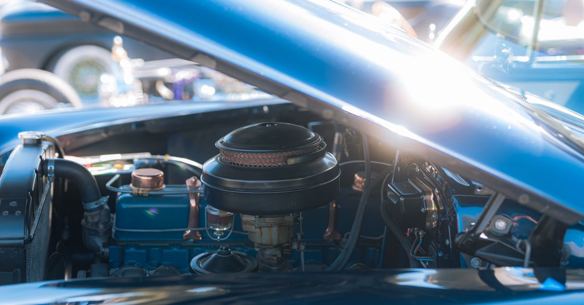 Nahaufnahme eines klassischen Oldtimer-Motors unter der Haube, der komplizierte Automobildetails präsentiert.