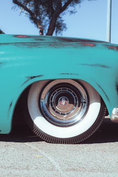 Detailed shot of a vintage blue car showcasing its retro design and whitewall tires.