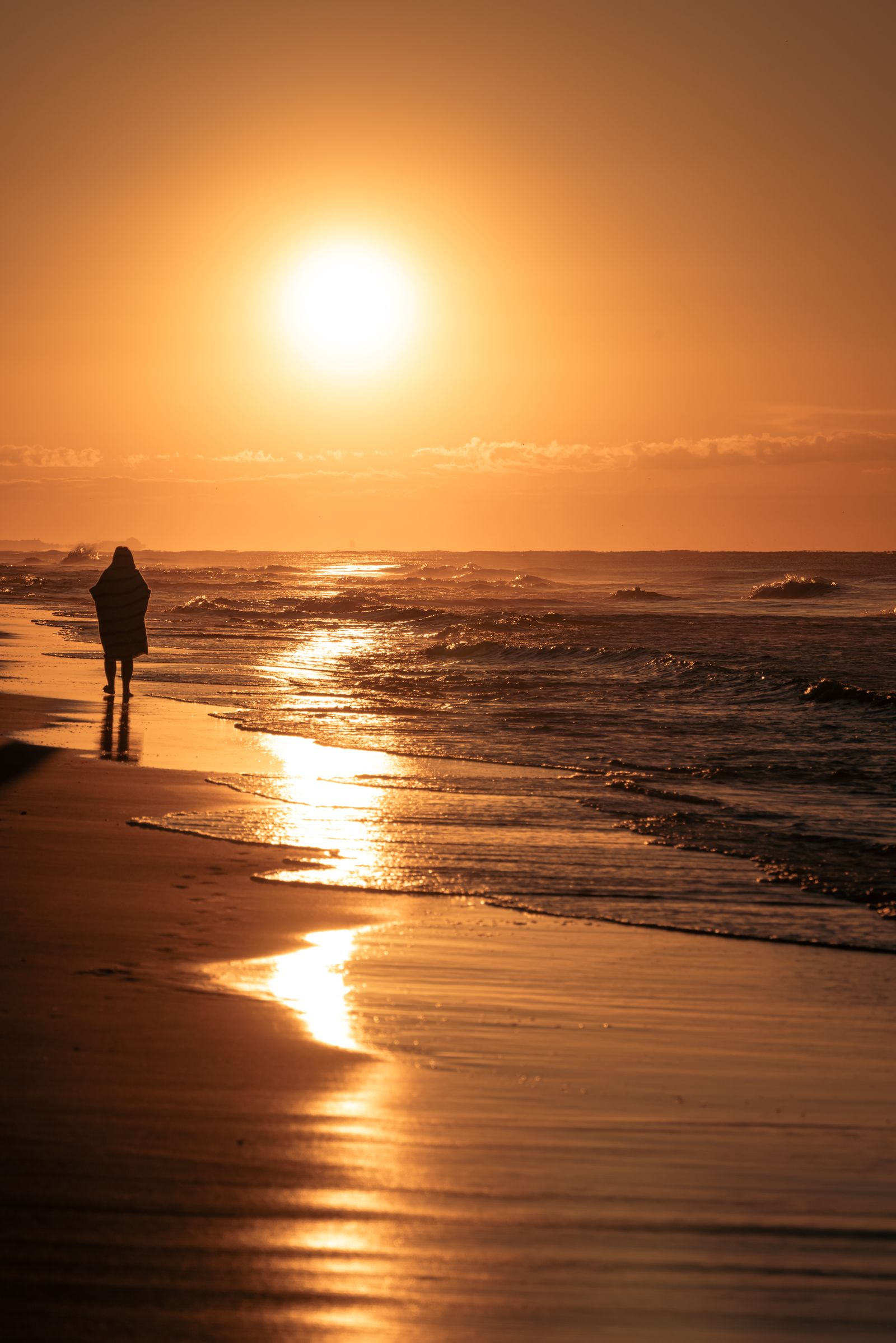Person walking along the beach at sunset