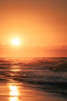 Gorgeous sunset casting golden hues over ocean waves, creating a serene seascape.