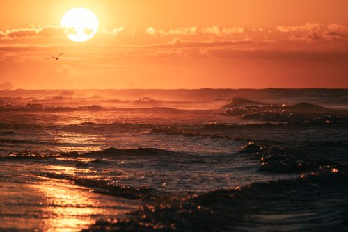 Free Mesmerizing view of the ocean waves under a vibrant sunset with golden hues. Stock Photo