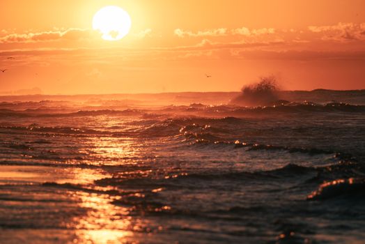 Experience the serene beauty of ocean waves crashing under a stunning golden hour sunset.
