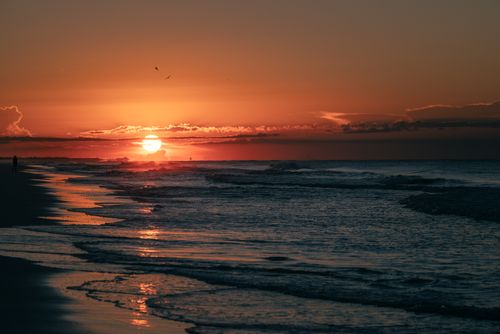 Free A breathtaking sunset over ocean waves, creating a serene and warm atmosphere at dusk. Stock Photo