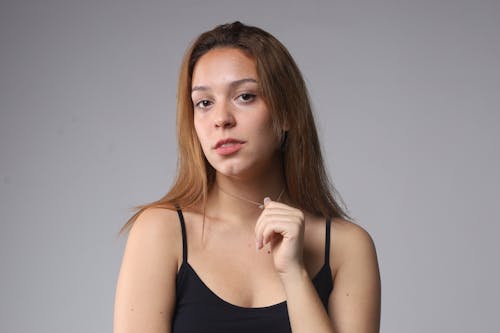 Woman in Black Tank Top Holding Her Necklace