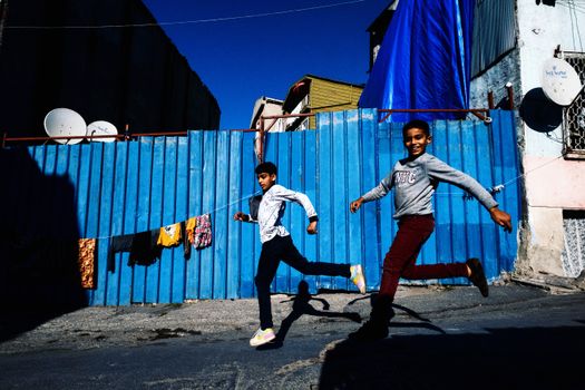 Two boys joyfully jump and play on a street in Istanbul, Turkey, showcasing youthful energy.
