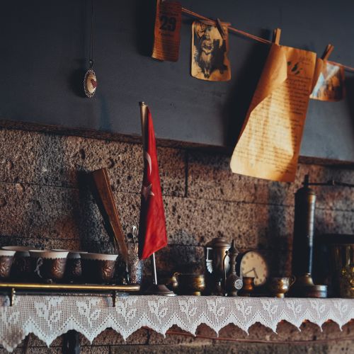 Free A cozy kitchen corner featuring vintage pottery, a Turkish flag, and antique decorations on a wooden shelf. Stock Photo