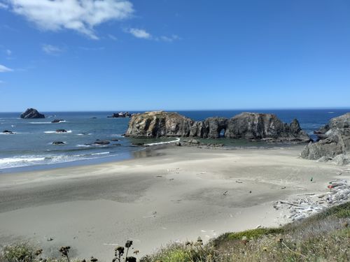 Free Dramatic coastal rock formations and a sandy beach under blue skies, perfect for nature lovers. Stock Photo