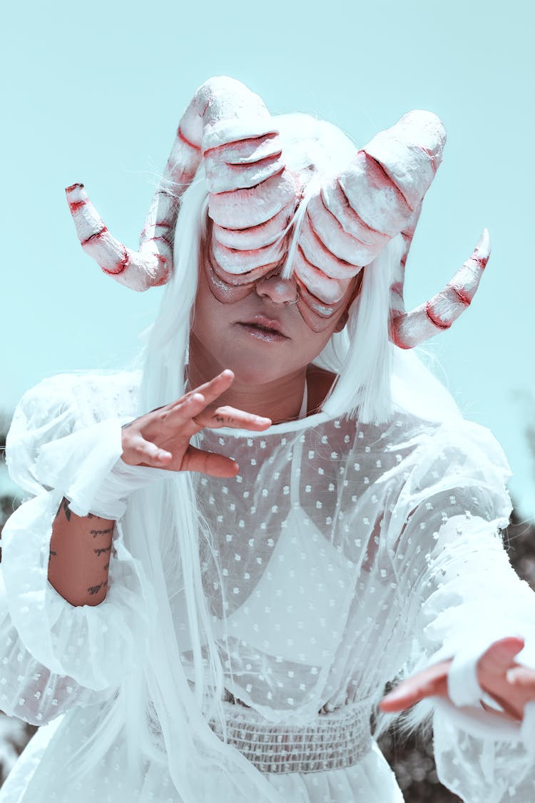 Woman In White Dress With Horns Covering Eyes