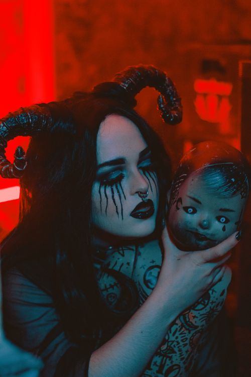 Free Dark fantasy portrait featuring a woman with dramatic makeup and a creepy doll. Stock Photo