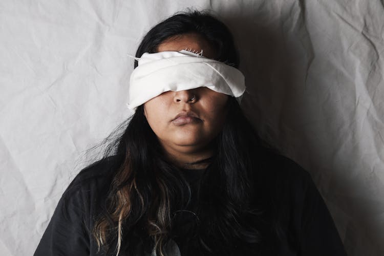 Woman Lying On Bed Wearing Blindfold