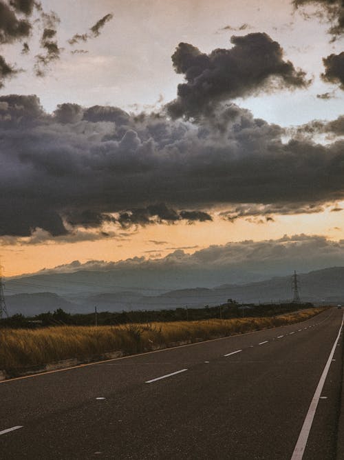 asfalt yol, bulutlu gökyüzü, dikey atış içeren Ücretsiz stok fotoğraf