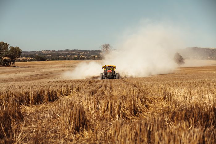 Yellow tractor working a golden hayfield