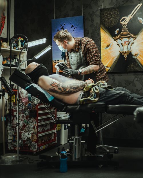 Free Tattoo artist in action creating intricate design at a modern tattoo studio. Stock Photo