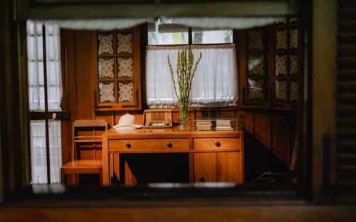 Free Warm-toned study room featuring a wooden desk, chair, and window with drawn curtains. Stock Photo
