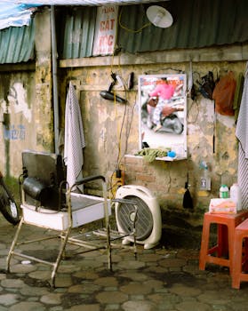 A vintage outdoor barber setup with rustic charm featuring a chair, mirror, and tools on a city street.