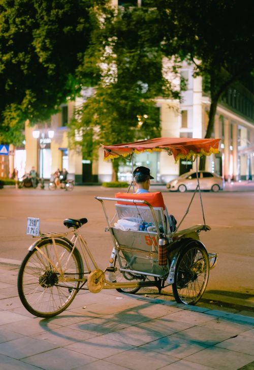 Free Man sitting on a tricycle on a city street at night in an urban setting. Stock Photo