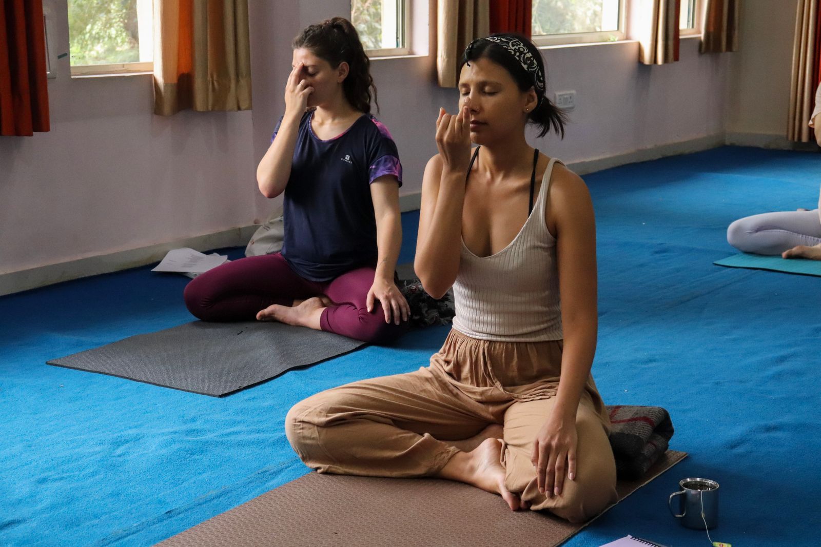 Two people practicing pranayama yoga breathing exercises indoors for lung health