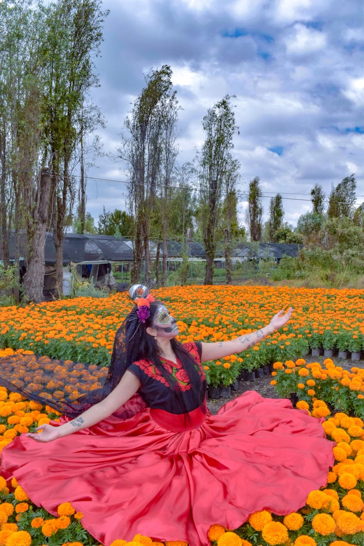 Woman Disguised As A Catrina With A Mexican Costume Sitting On A Flower Field