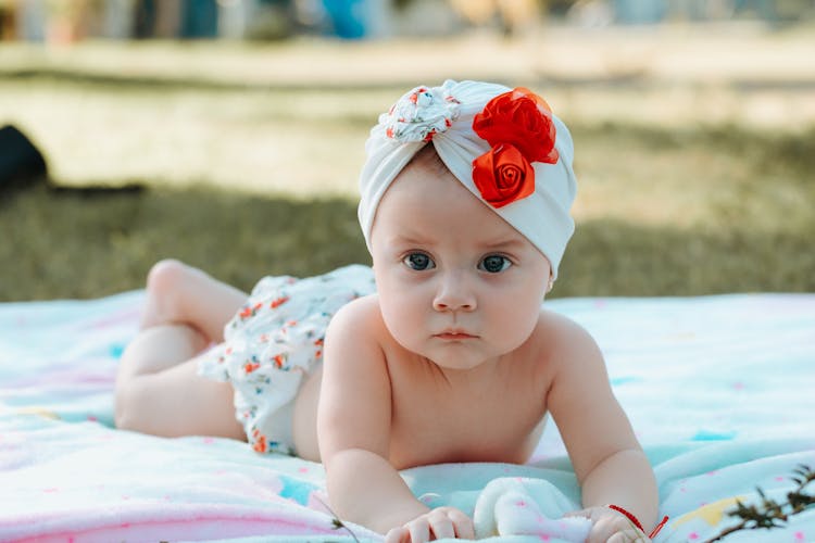 Baby Wearing Turban And Skirt Lying On Blanket