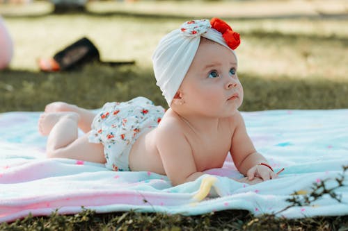 Free Close-Up Shot of a Cute Baby Lying on Picnic Blanket Stock Photo