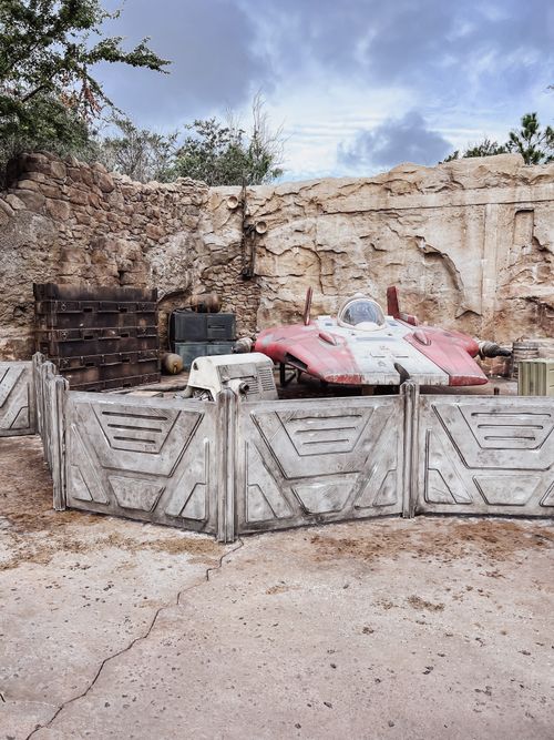 Free A deserted sci-fi vehicle surrounded by rocky terrain and a futuristic fence under a cloudy sky. Stock Photo