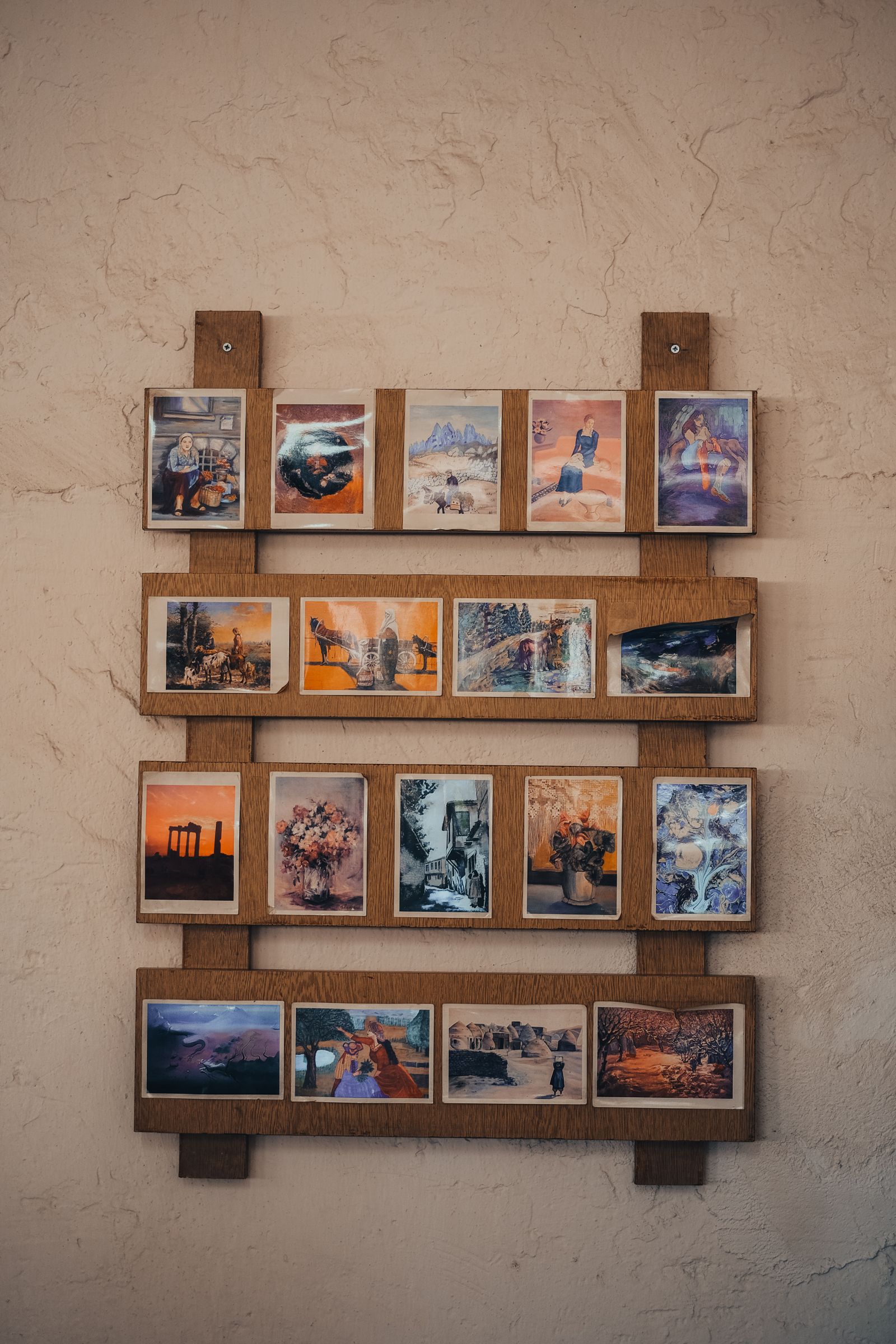 A wooden rack of printed photos mounted on a wall, ready to sell.