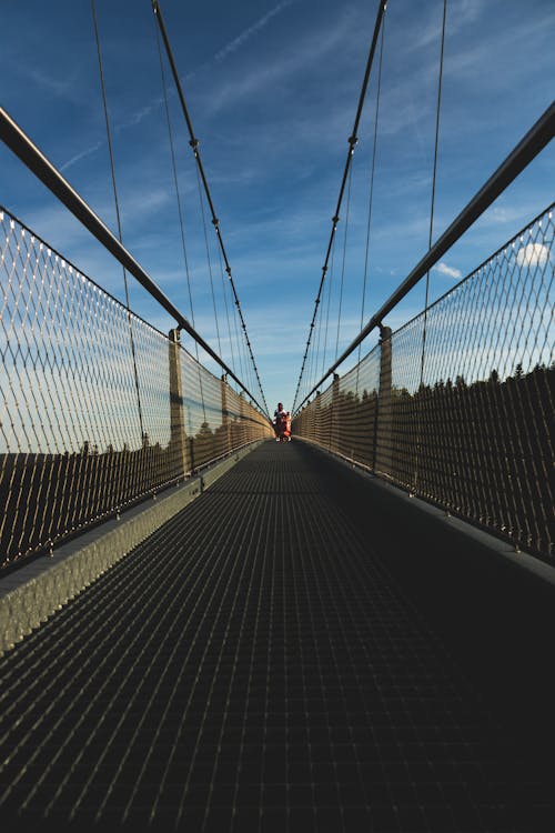 A Biker Crossing a Narrow Suspended Bridge