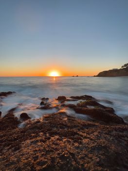 A captivating sunset over the rocky coastline of Laguna Beach, California, showcasing serene ocean waves.