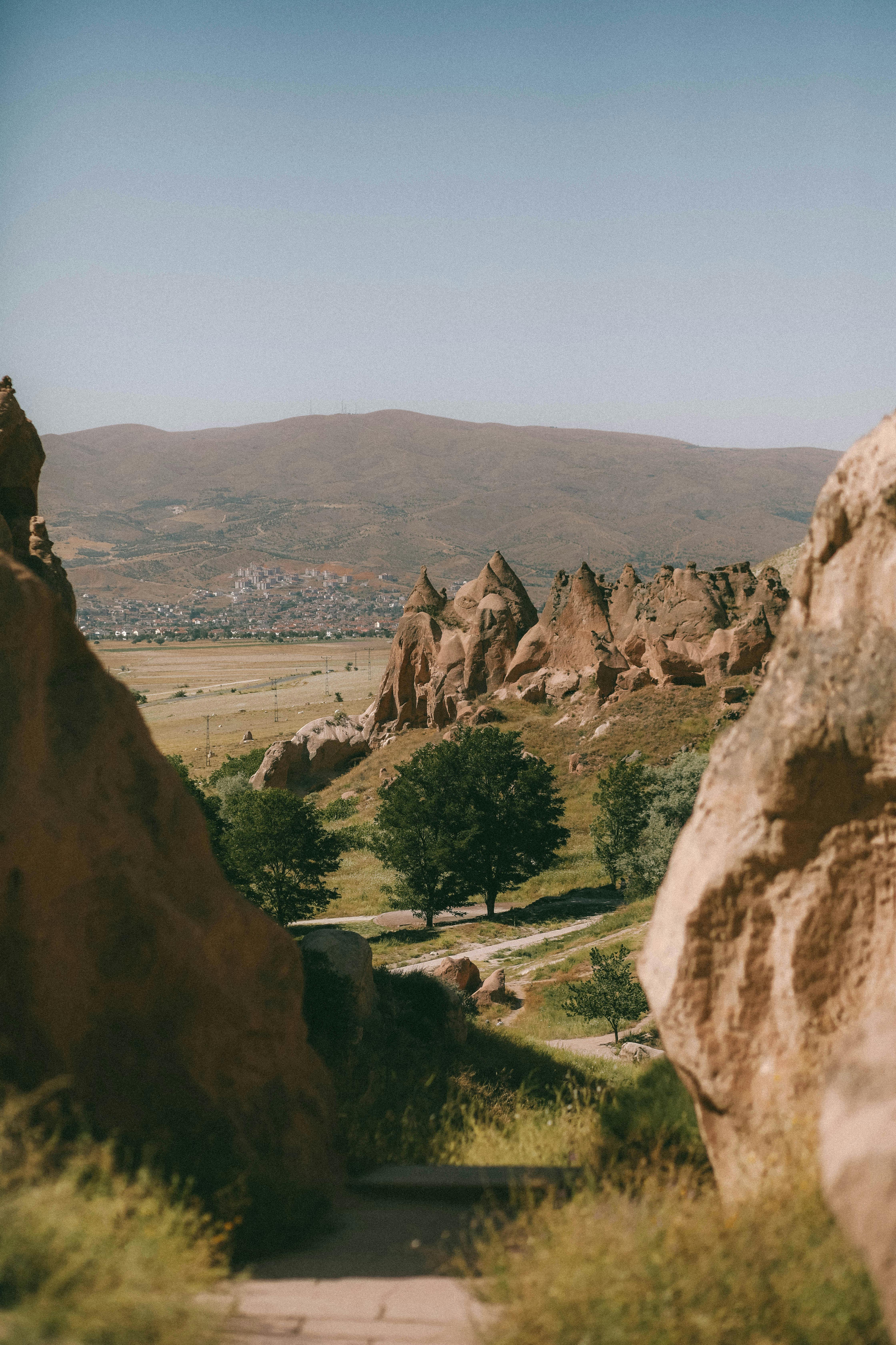 Discover Cappadocia's stunning rock formations and lush greenery under a clear blue sky.