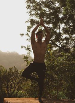 A man practices a yoga pose outdoors during sunrise in Jaipur, India.