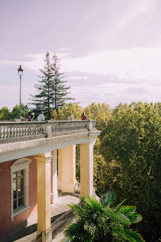 Charming terrace of a French villa in Pau, France, surrounded by lush greenery under a bright sky.