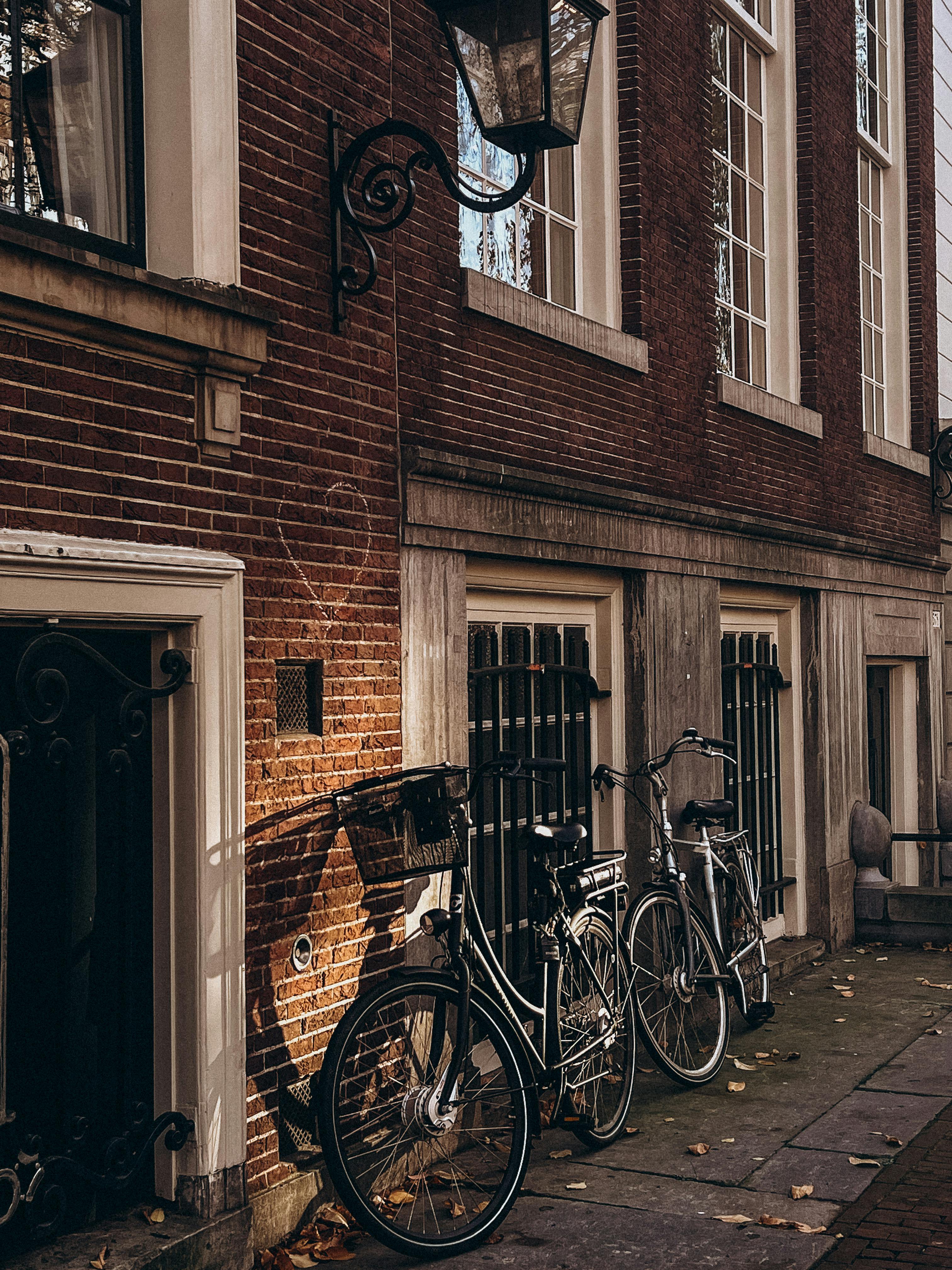 Bicycles parked by a brick building facade under warm sunlight.