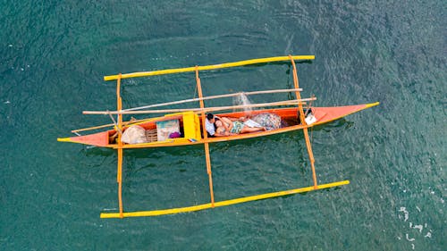 People Riding on Yellow and Orange Boat on Body of Water