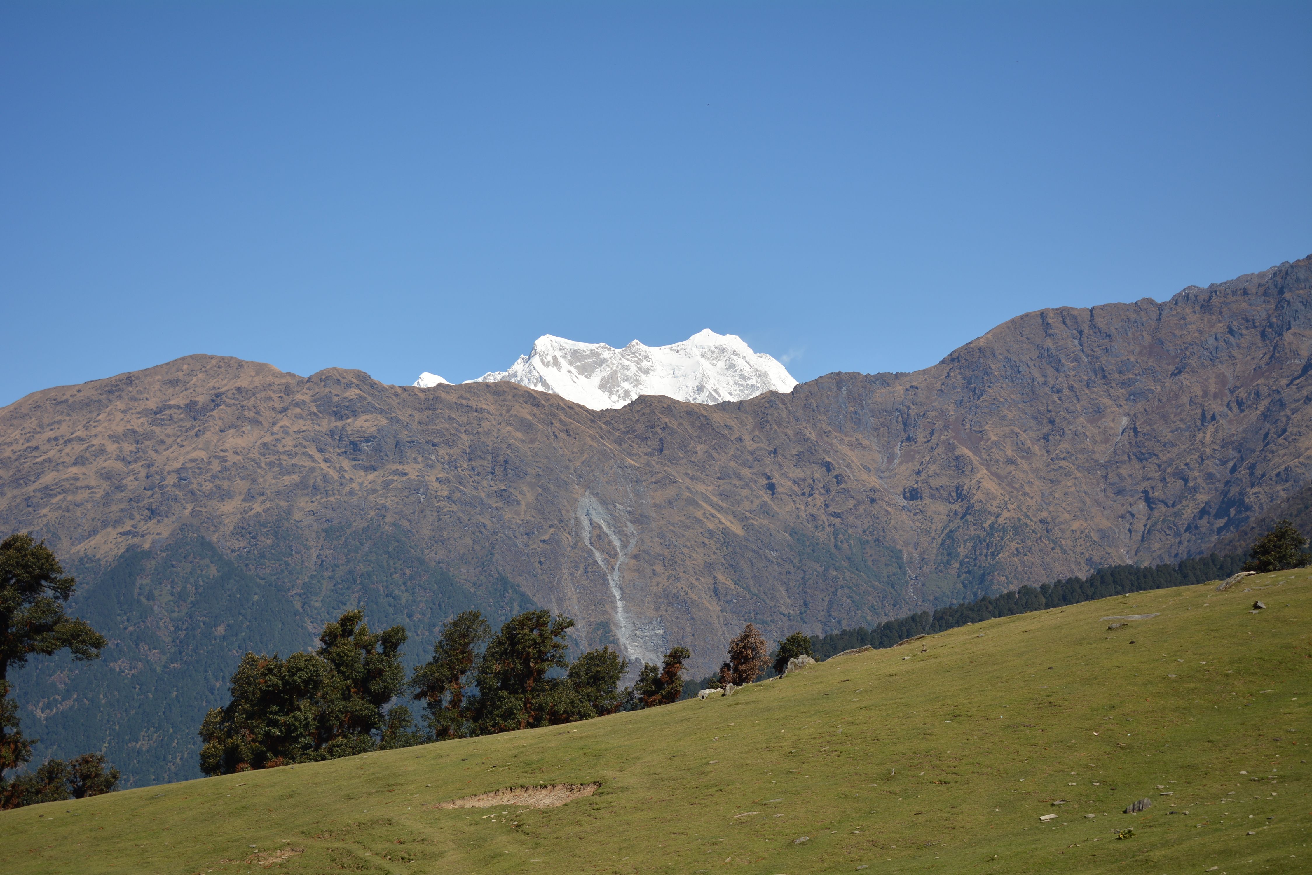 Stunning view of a mountainous landscape with clear skies and lush green foreground, ideal for nature enthusiasts.