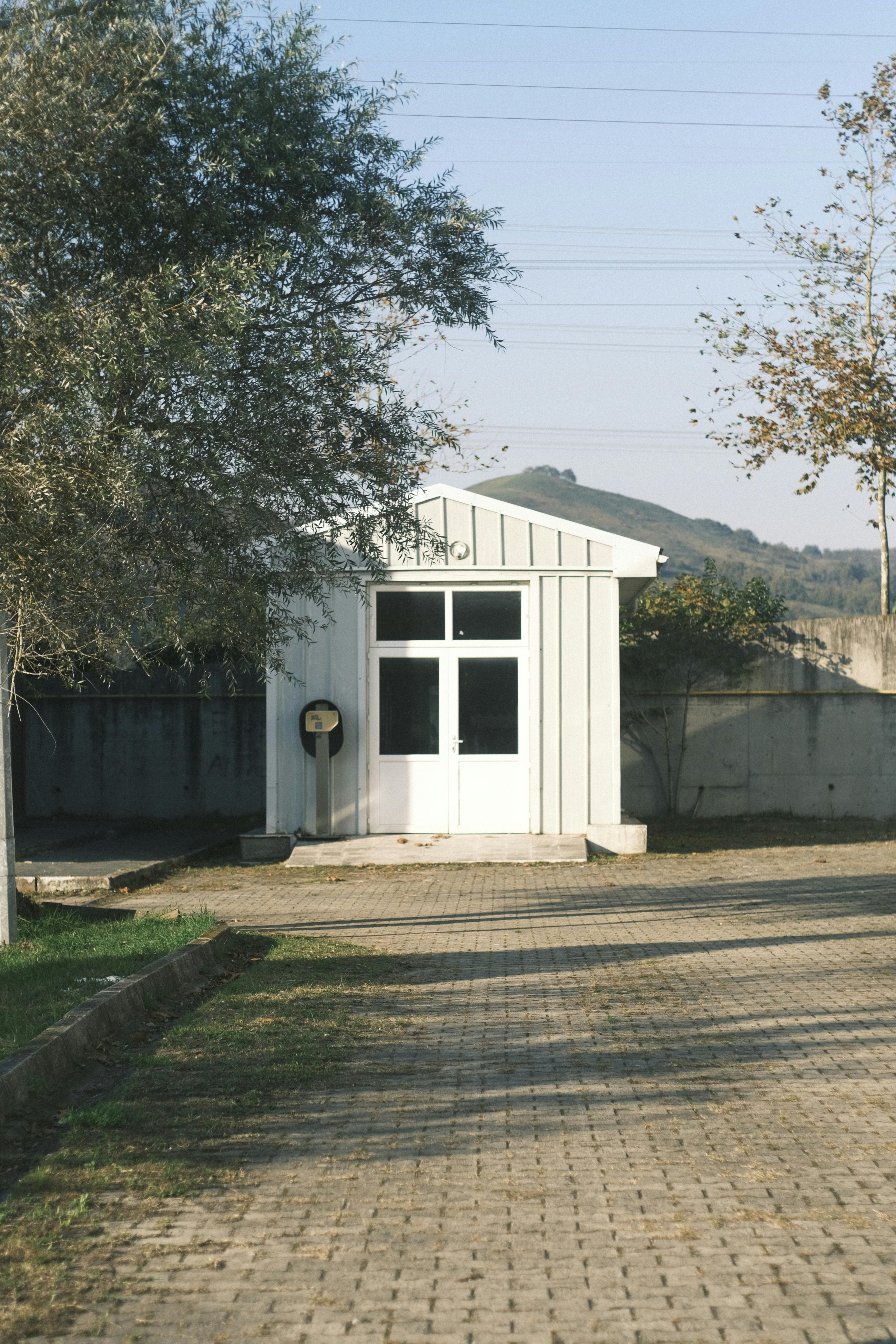 A quaint small wooden house sits outdoors, surrounded by nature and a clear sky, offering a serene atmosphere.