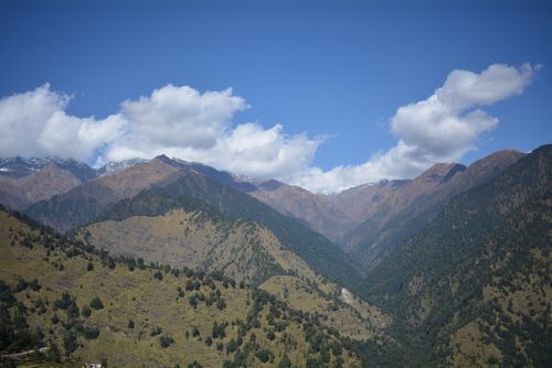 Free A breathtaking view of a lush mountain range under a vibrant blue sky with fluffy clouds. Stock Photo