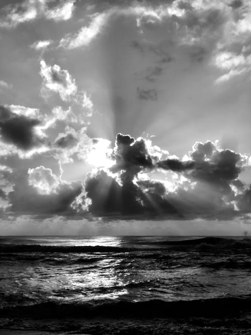 A Sun Behind Clouds Over the Sea in Grayscale Photo