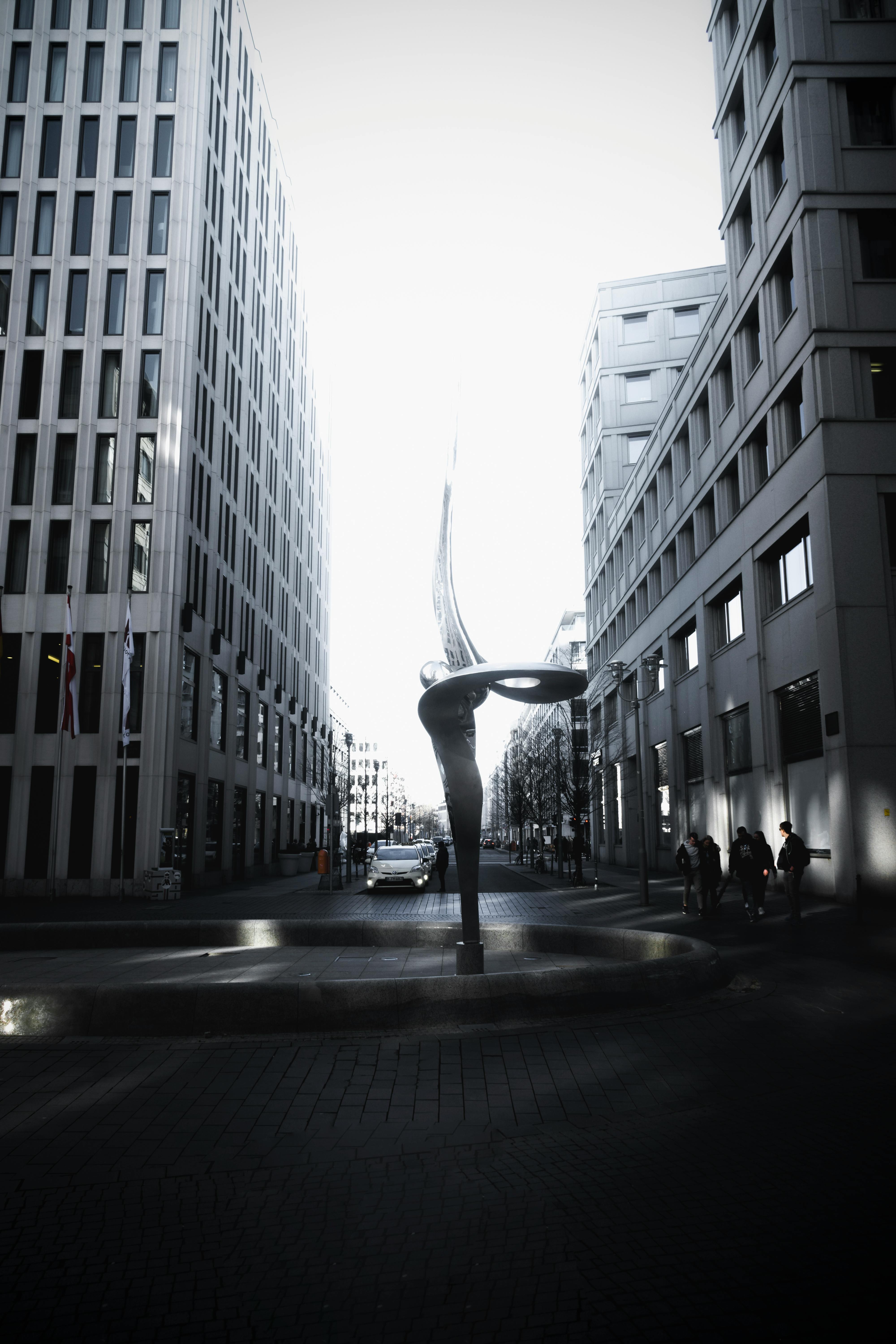 柏林现代建筑间的雕塑艺术旁，行人与车辆川流不息