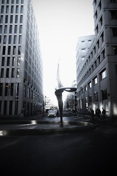 柏林现代建筑间的雕塑艺术旁，行人与车辆川流不息