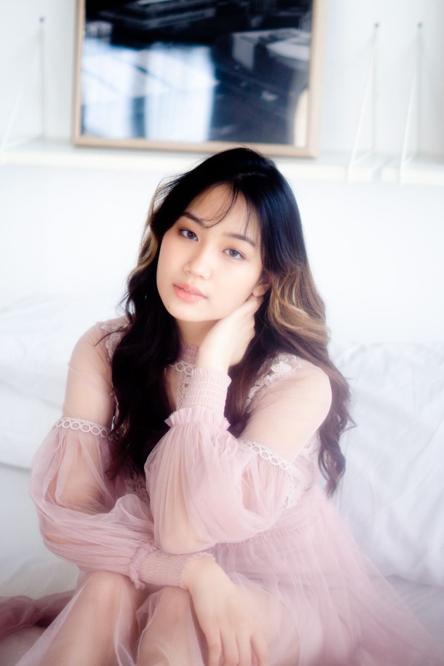 Elegant portrait of a woman in a pink tulle dress, sitting on a couch, indoors.