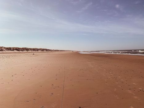 A tranquil sandy beach scene with clear sky and gentle waves at Henne, Denmark.