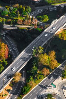 Aerial shot of vehicles on a highway interchange surrounded by greenery.