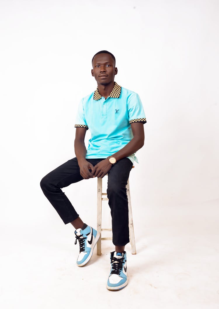 Man In Polo Shirt And Black Pants Sitting On A Stool