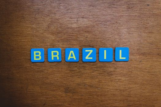 Close-up image of the word 'Brazil' spelled with blue tiles on a wooden surface, flat lay style.