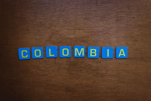 A close-up of colorful tile letters spelling 'Colombia' on a wooden surface.