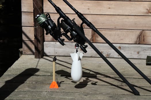 Close-up of fishing rods and accessories on a dock in sunlight.