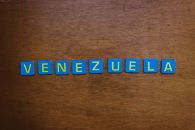 Blue and yellow letter tiles spelling Venezuela on a wooden surface.