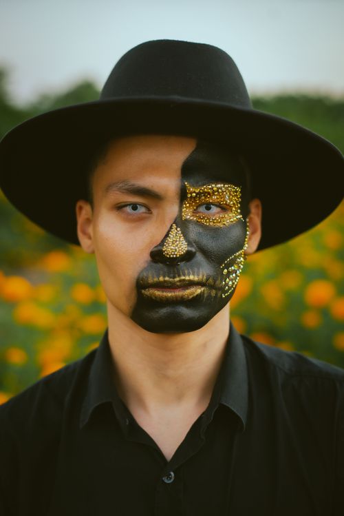 Free Intriguing portrait of a man in black face paint and hat, inspired by Dia de los Muertos. Stock Photo